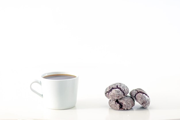 Minimal designed scene a coffee cup and dark chocolate cookie over plain white background includes copy space