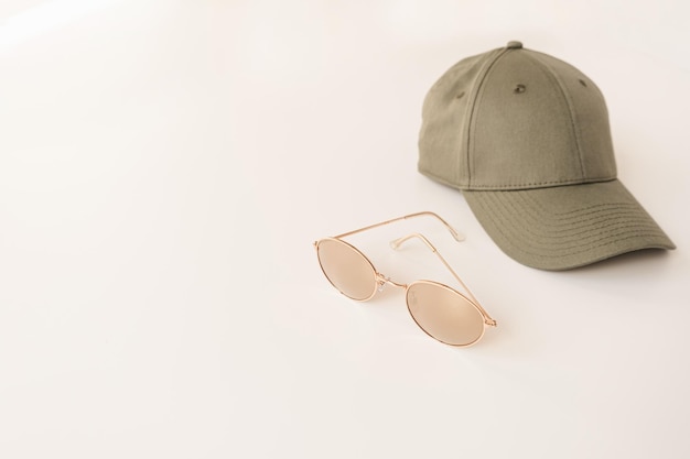 흰색 배경 선글라스와 중립 모자에 스포츠 여성용 액세서리를 사용한 최소한의 패션 개념