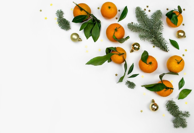 Minimal flat lay Christmas composition of fir tree branch, tangerine and balls