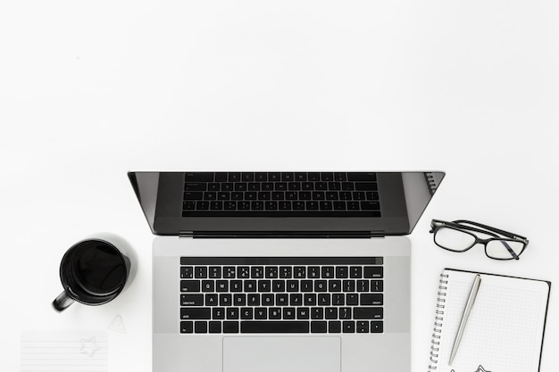 Minimal freelancer office workplace flat lay top view Worksplase with laptop, notebook, pen, glasses and coffee cup