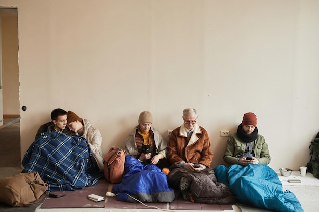 Minimal front view at diverse group of refugees hiding in\
shelter together during war or crisis copy