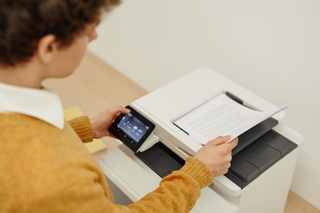 Minimal high angle shot of young man copying documents in office copy space