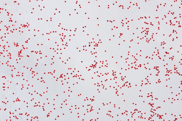 Minimal holiday texture with red confetti on grey