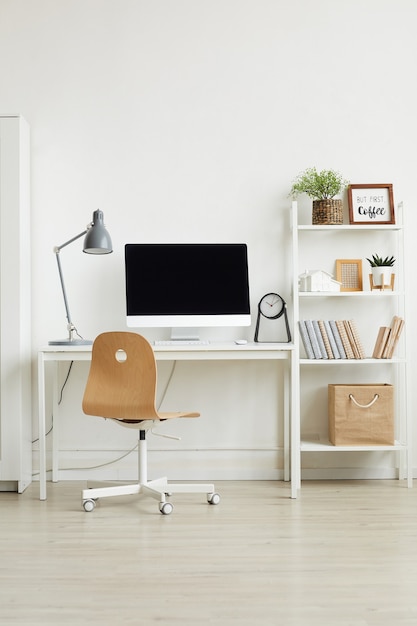 Фото Минималистичный интерьер домашнего офиса с деревянным стулом и белым компьютерным столом у белой стены