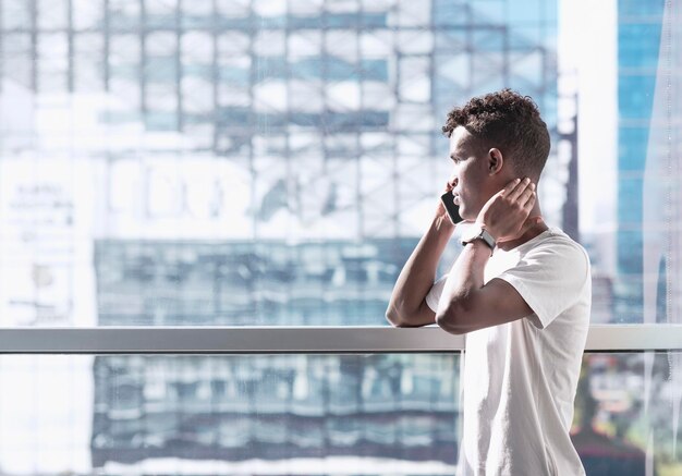 Minimal looking portrait of young African Black man he is talking with a mobile phone in a modern office elegant image with pure colors and copy space