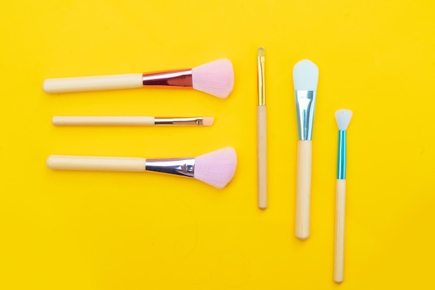 Minimal modern cosmetic scene with set of make up brushes set over yellow background