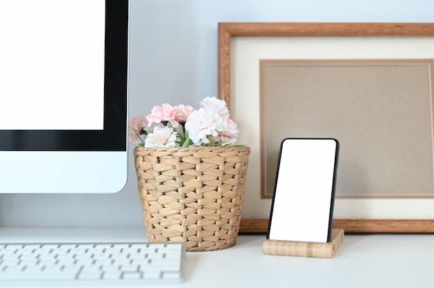 白いテーブルの上に空白の画面のスマートフォンと最小限のオフィスデスク