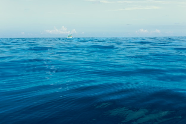 青い海の波に浮かぶ漁船の最小限の写真