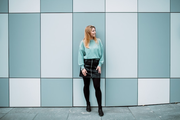 Minimal portrait of a beautiful young girl standing against blue wall