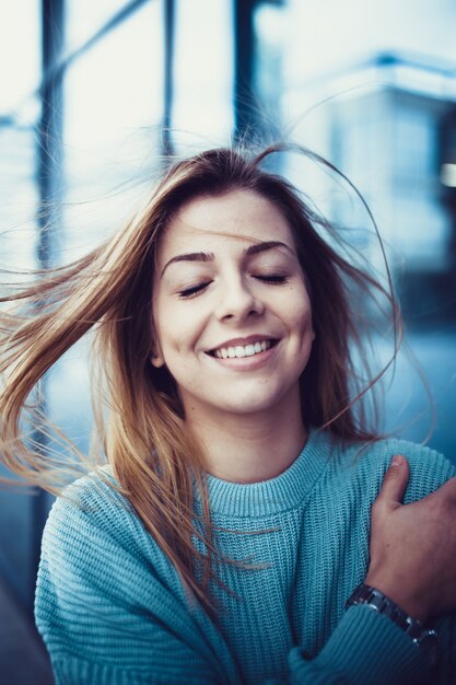 Minimal portrait of a beautiful young girl standing against blue wall