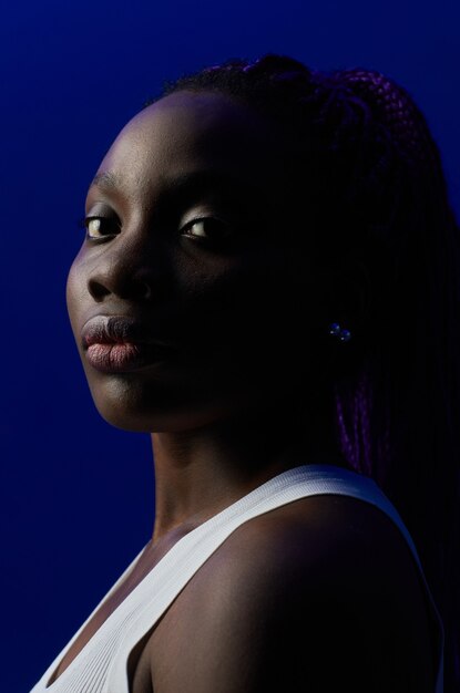 Minimal portrait of confident African-American woman looking at camera while standing against purple background in studio