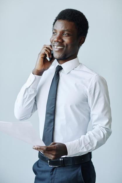 Minimal portrait of professional black businessman speaking on phone against white background