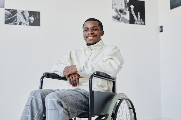 Minimal portrait of smiling black man using wheelchair while visiting modern art gallery copy space