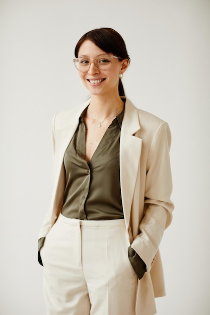 Minimal portrait of successful young woman smiling at camera while standing against neutral background