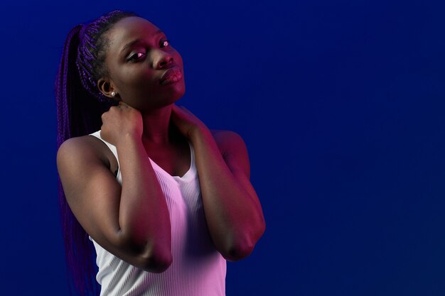 Minimal portrait of young African-American woman looking at camera lit by purple in studio, copy space