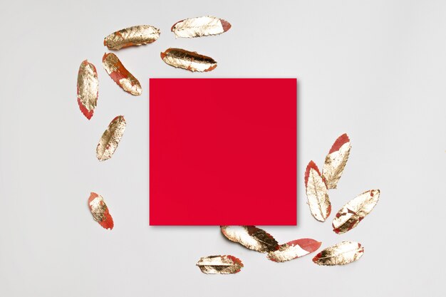 Minimal red paper frame with gold leaves on a gray background.