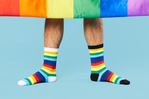 Minimal shot of couple wearing rainbow socks with lgbtq flag on pastel blue background copy space