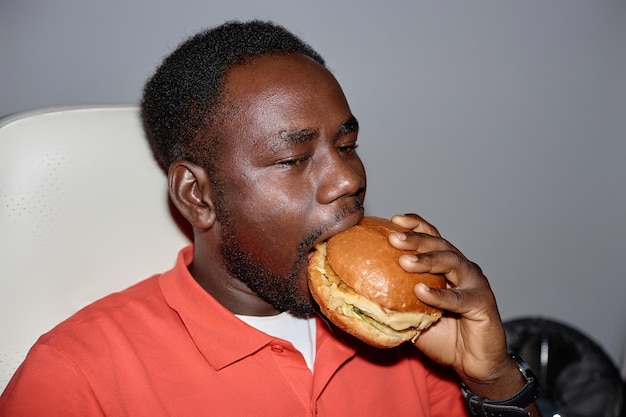 실내에서 햄버거를 먹는 최소한의 측면 보기 흑인