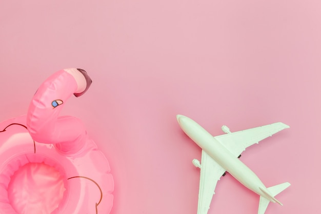 Minimal simple flat lay with plane and Inflatable flamingo isolated on pastel pink background
