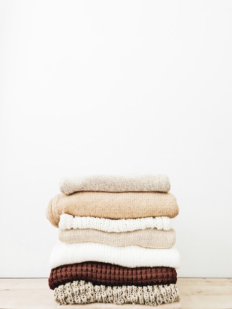 A minimal stack of warm beautiful feminine sweaters or pullovers lying on wooden table