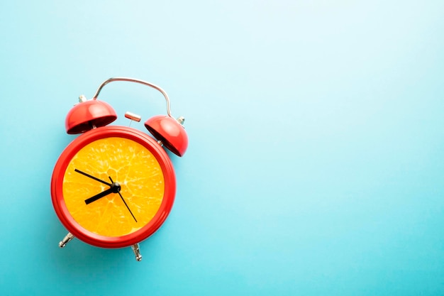 Minimal still life image of an alarm cloch with fresh orange inside