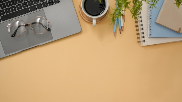 Minimal stylish office desk with laptop computer and copy space on pastel yellow background top view