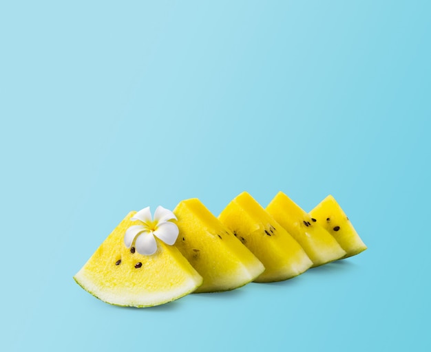 Minimal summer design of yellow watermelon with white flower on blue background 