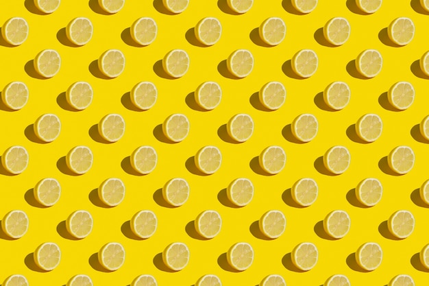 Minimal sunny summer flat lay fruit background. Fresh lemon slices on yellow background pattern.