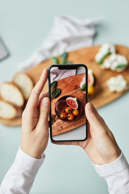 Photo minimal top view of young woman taking aesthetic photo of food using smartphone in home studio