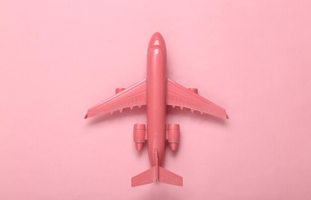 Minimal travel layout Pink plane on pink background Flat lay Top view