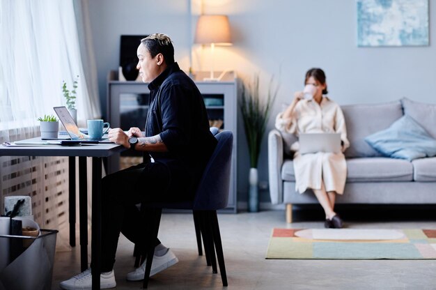 Minimal view at two young women at home focus on person working at table in foreground copy space