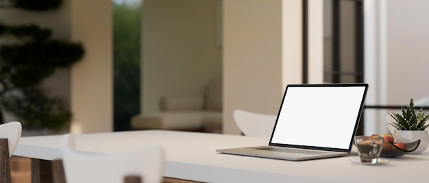 Минимальный белый обеденный стол в минималистичной удобной столовой с макетом ноутбука