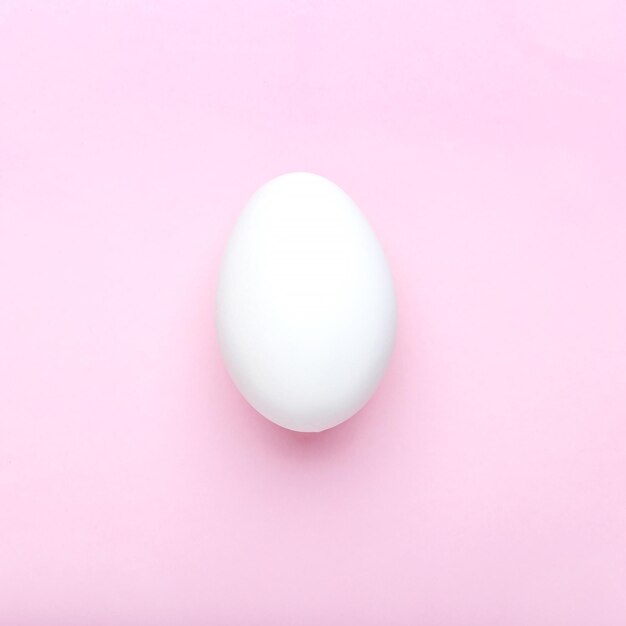 Foto uovo di pasqua bianco minimo su sfondo rosa piatto