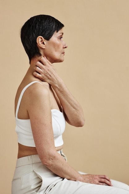 Minimal of woman scratching neck against neutral background