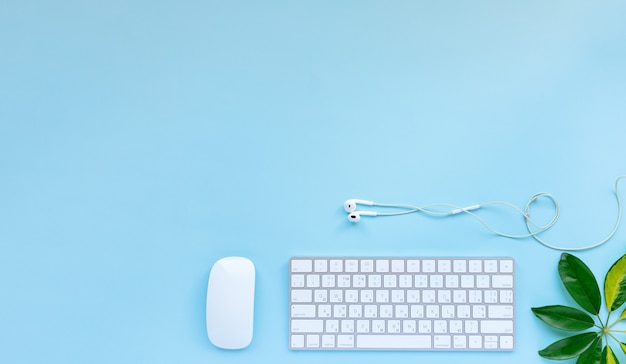 Minimal work space - Creative flat lay photo of workspace desk. Top view office desk with keyboard and mouse on blue color background. Panoramic banner background with copy space.