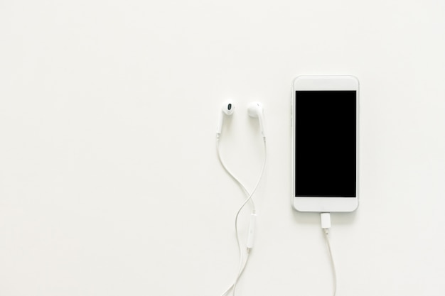 Minimal work space - Creative flat lay photo of workspace desk with earphones and mobile phone with blank screen on copy space white background. Top view mock up , flat lay photography.