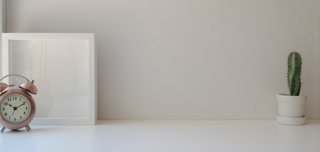 Minimal workplace with copy space and mock up frame on white wooden table and white wall 