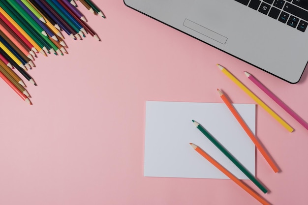 Minimal workplace with laptop and blank notepad on pink background