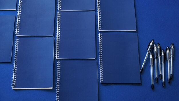 Minimal workspace with blue notebooks on a blue background Office concept Mockup Top view