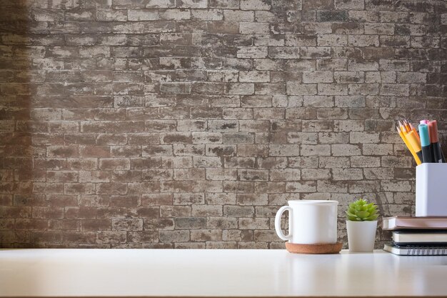 Minimal workspace with book coffee cup and pencil holder on white table Copy space for your advertising text