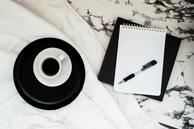 Minimal workspace with coffee cup, notebook with copy space on stylish marble background