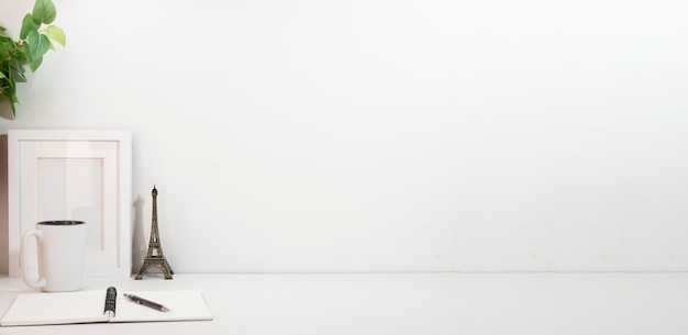 Photo minimal workspace with houseplant coffee cup picture frame and stationery on white table copy space for text