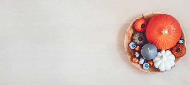 Minimale halloween-decoratiebanner met pompoenensuikergoed zwarte kaarsen op houten tafel