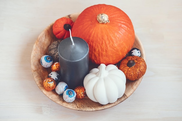 Minimale halloween-vakantiedecoratie met pompoensnoepjes zwarte kaarsen op houten tafel binnenshuis