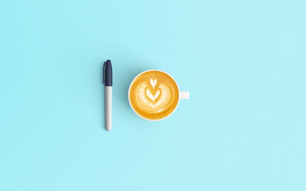 Foto minimale werkruimte met latte koffiekopje en pen op blauwe kleur