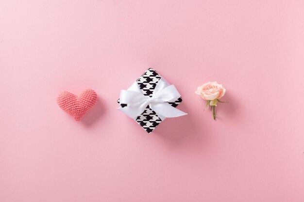 Minimalism background for Valentine's Day A banner layout with a knitted heart a gift and a rose on a light