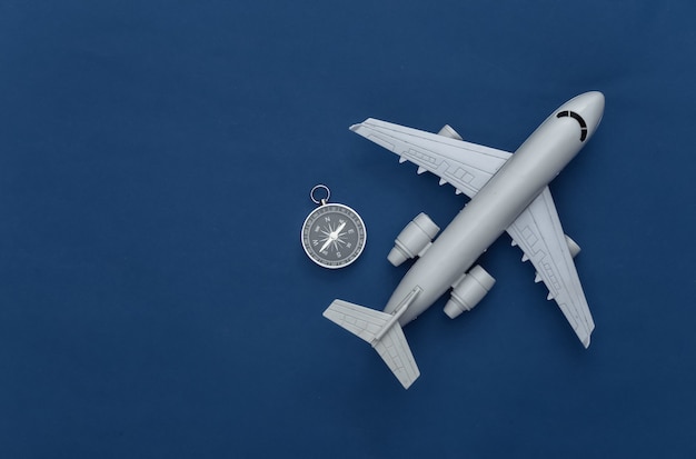 Minimalism travel flat lay. Compass and air plane on classic blue background. Top view