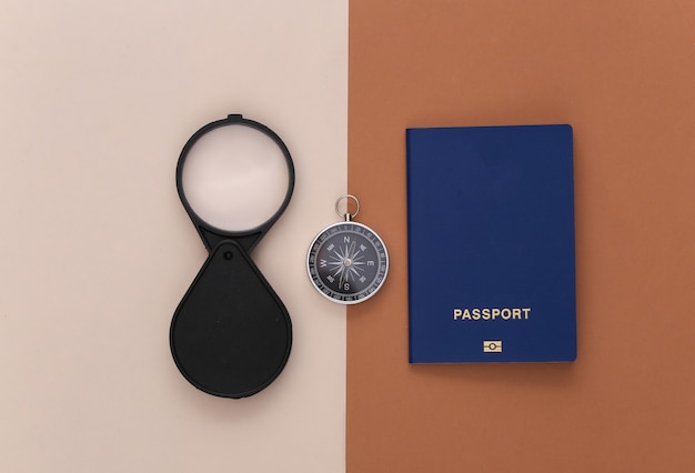 Minimalisme reizen, avontuur plat leggen. Kompas en vergrootglas, paspoort op bruin beige achtergrond. Bovenaanzicht