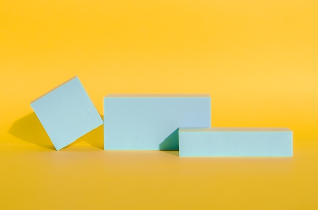 Minimalist abstract background. three-dimensional geometric shapes in light blue on yellow background. Modern style, product podiums, art. Selective focus, space for text