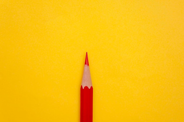 Minimalist background red pencil on yellow background with copy space